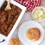 Bun on a plate, slow cooker pulled pork in serving dish.