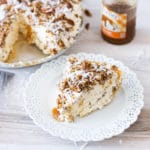 Slice of frozen pecan pie on a plate, caramel topping on counter.