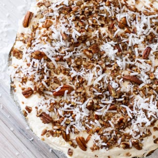 Whole pie topped with toasted pecans and shredded coconut sitting on a counter.