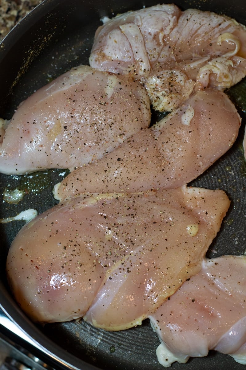 Sauteing 5 pieces of chicken in a skillet.
