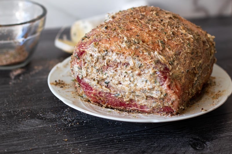 Prime rib covered in compound butter sitting on a plate.