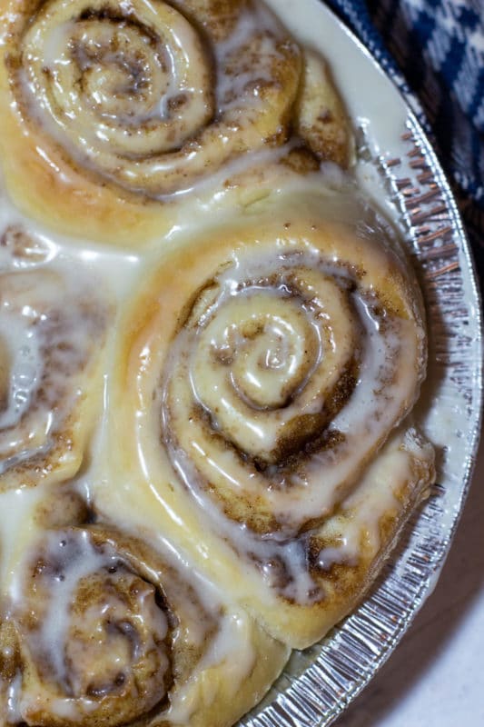 Cinnamon rolls in a baking pan topped with vanilla icing.