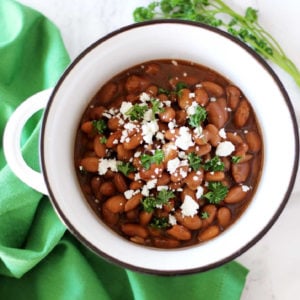 White bowl containing pinto beans topped with feta cheese.