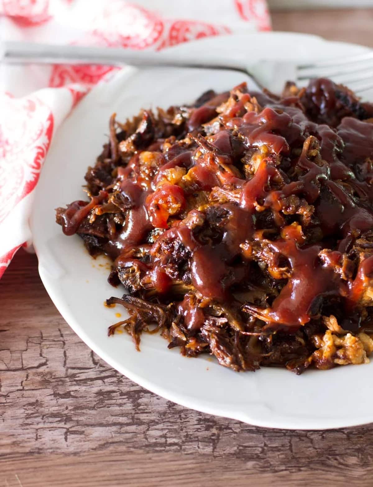 Plate filled with beef short ribs covered in bbq sauce.