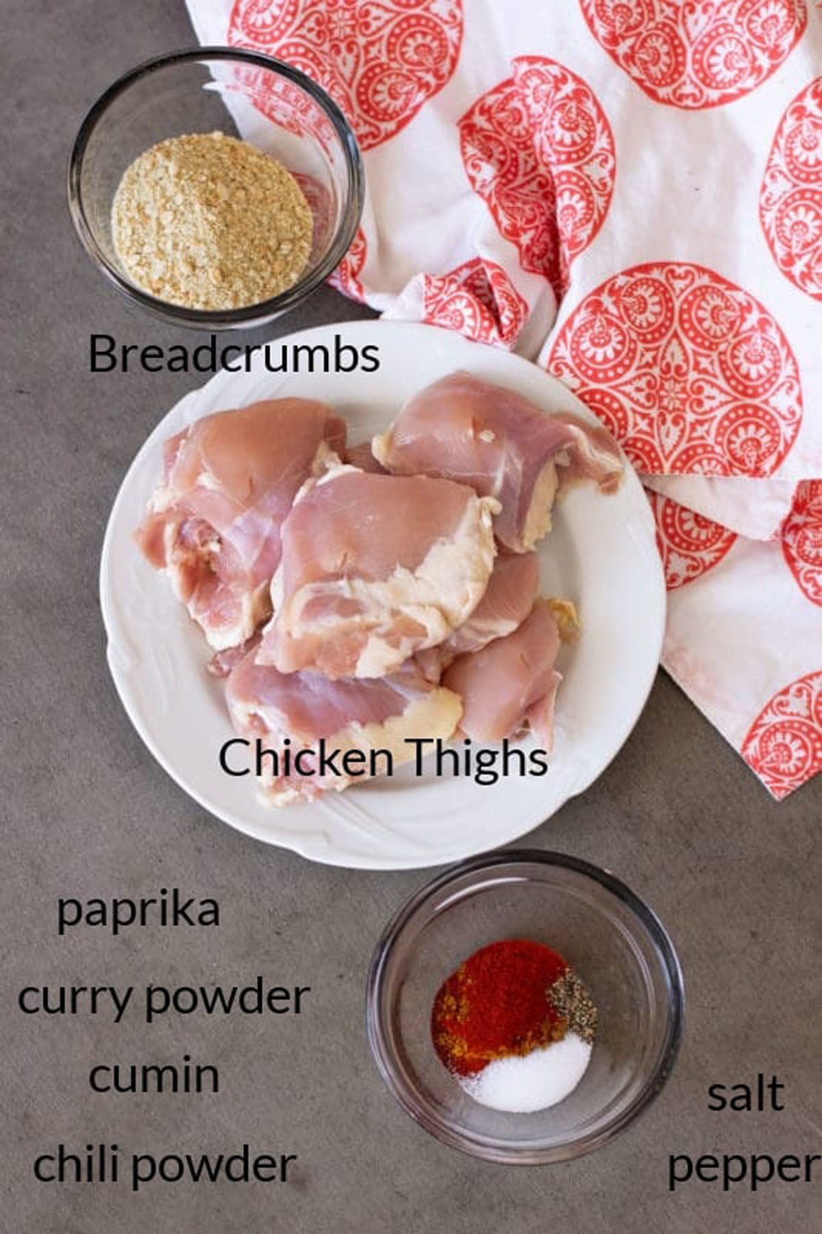 Ingredients including chicken, breadcrumbs, and spices on a counter.
