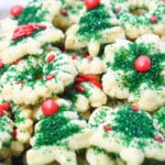 Spritz cookies on a platter topped with green sprinkles.
