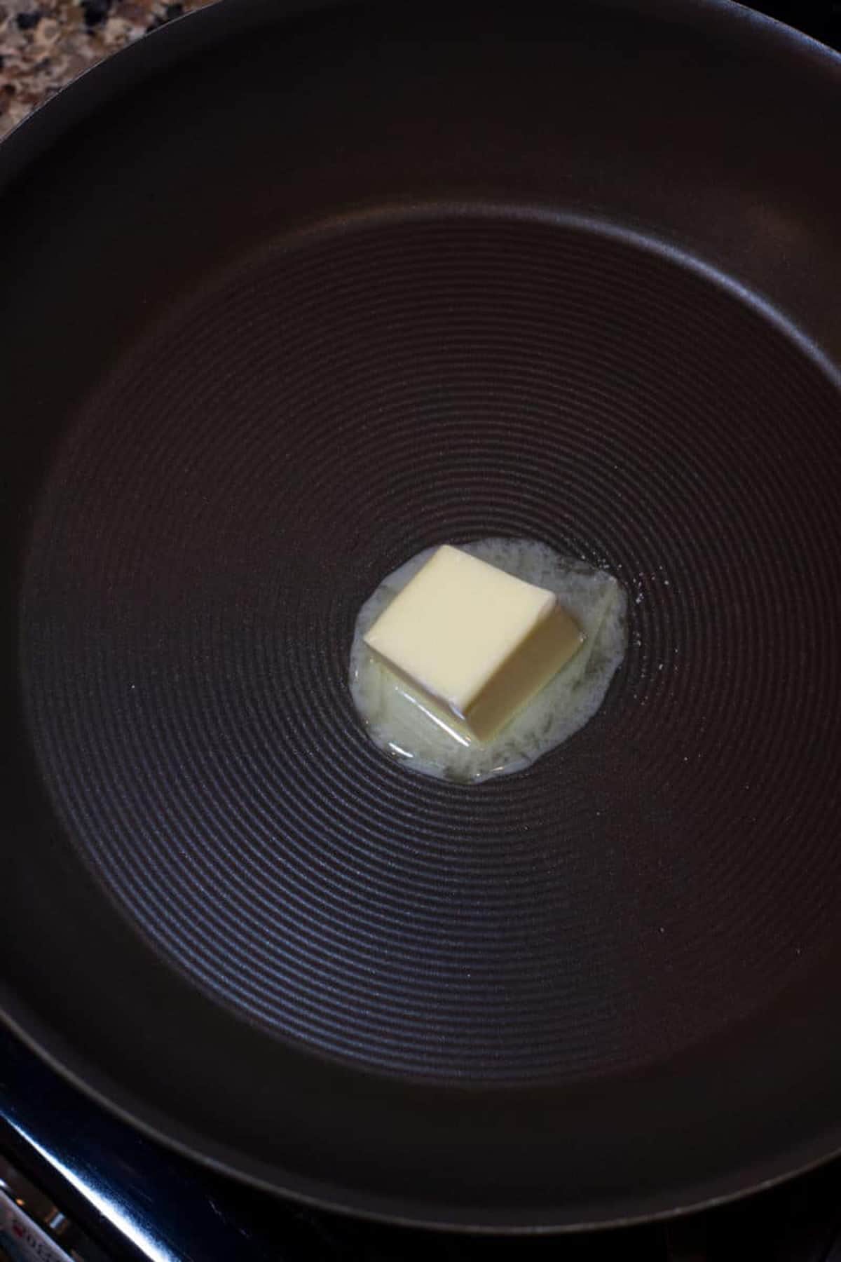Butter melting in a pan on stove top.