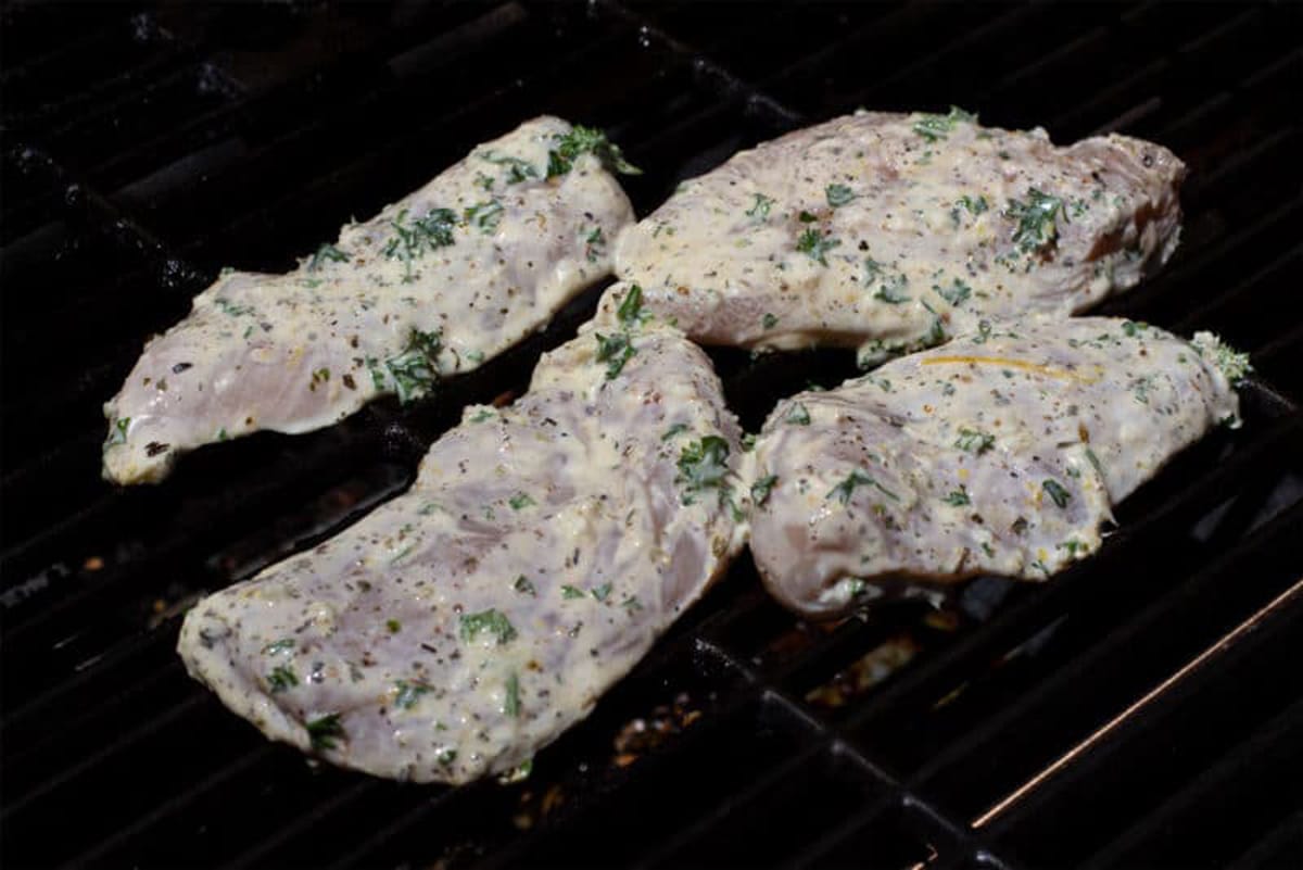 4 pieces of Greek marinated chicken on the grill.
