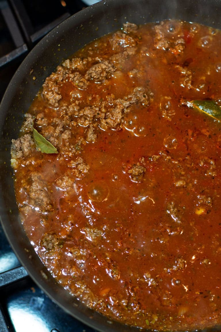 Homemade authentic Italian marinara sauce cooking in a skillet on a stove.