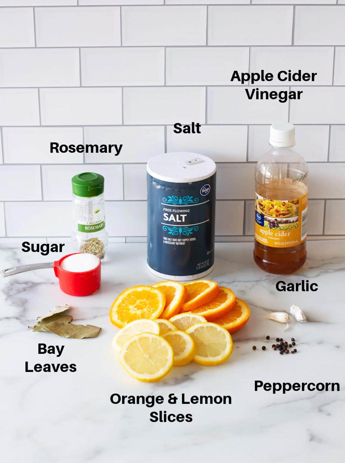 Brine ingredients on a counter containing lemon, orange, sugar, salt, and apple cider vinegar.