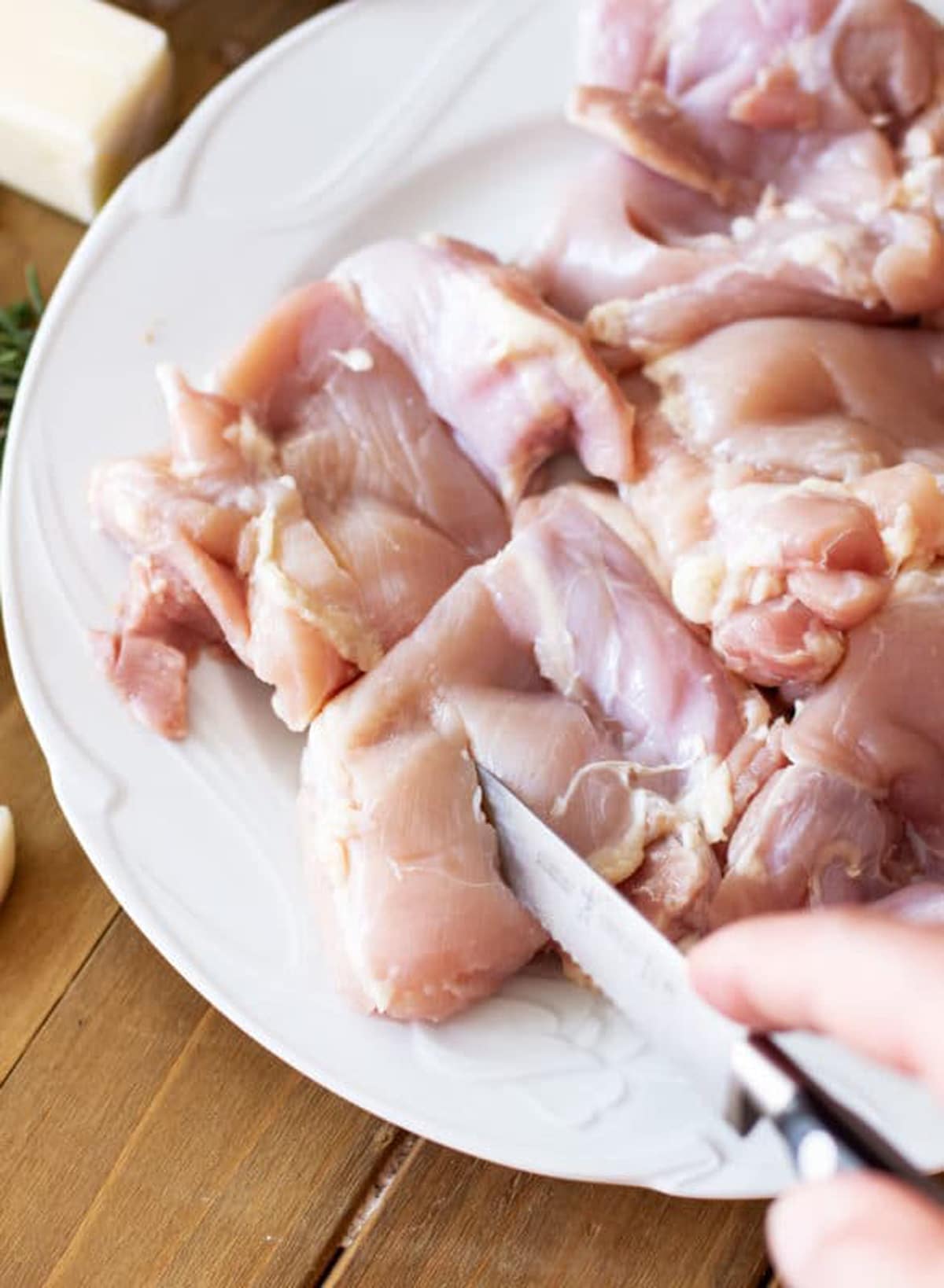 Person cutting a slit in raw chicken thighs in preparation for marinade.