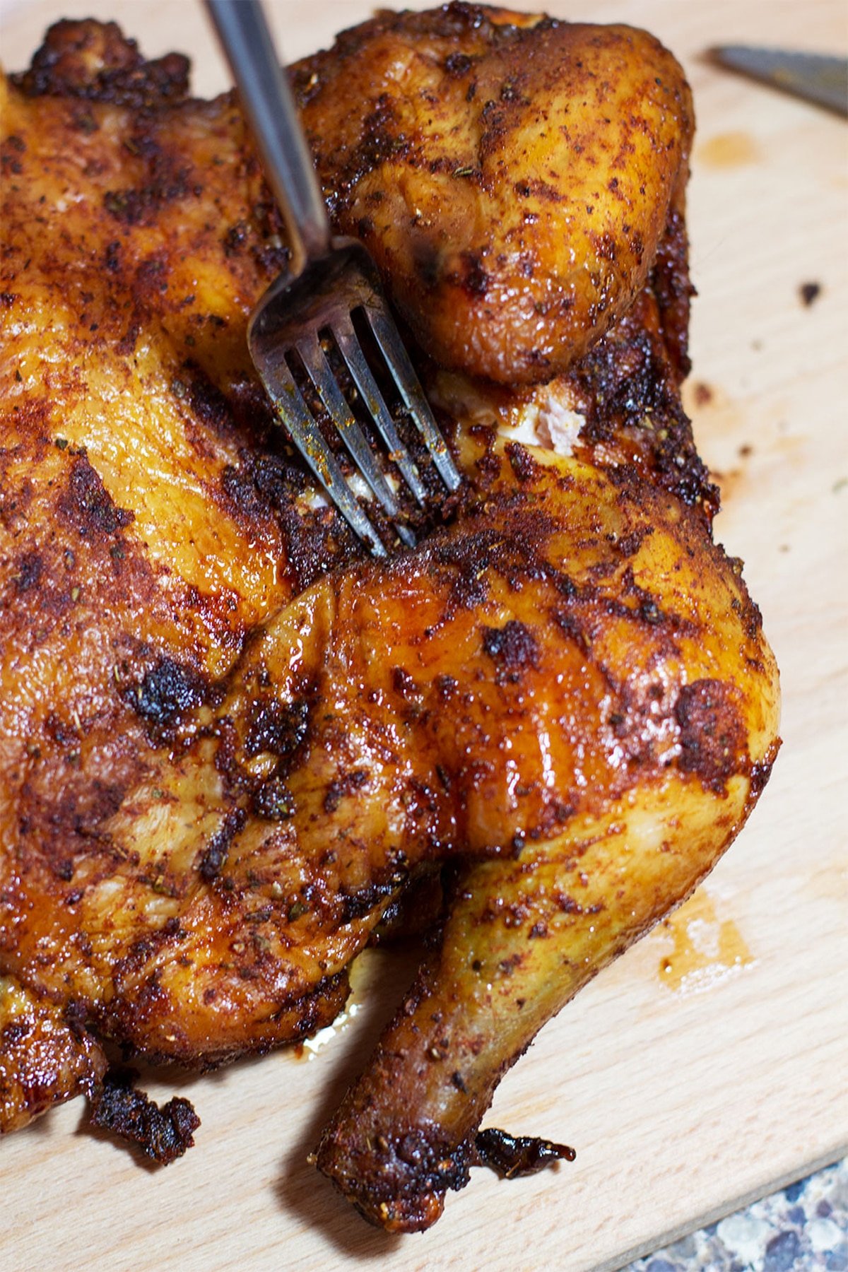 Applewood Smoked Chicken on a wooden cutting board, fork in chicken.