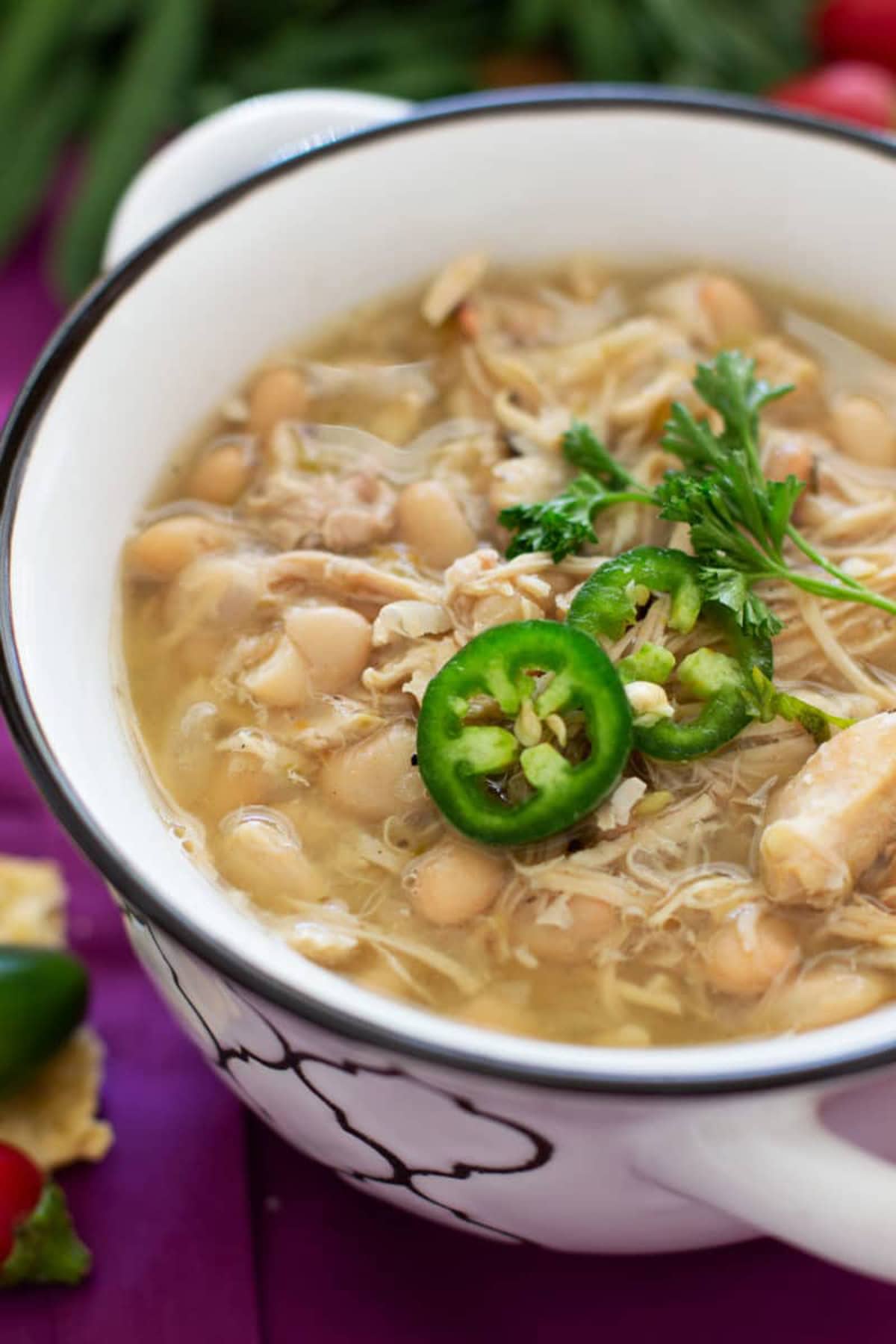 Close up of a bowl of white chicken chili topped with jalapenos and cilantro.