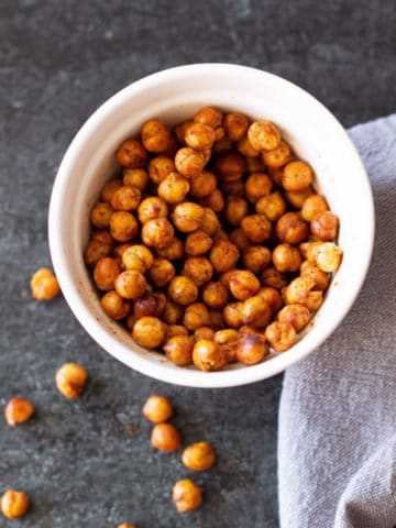 White bowl containing chili lime seasoned chickpeas on a black counter.