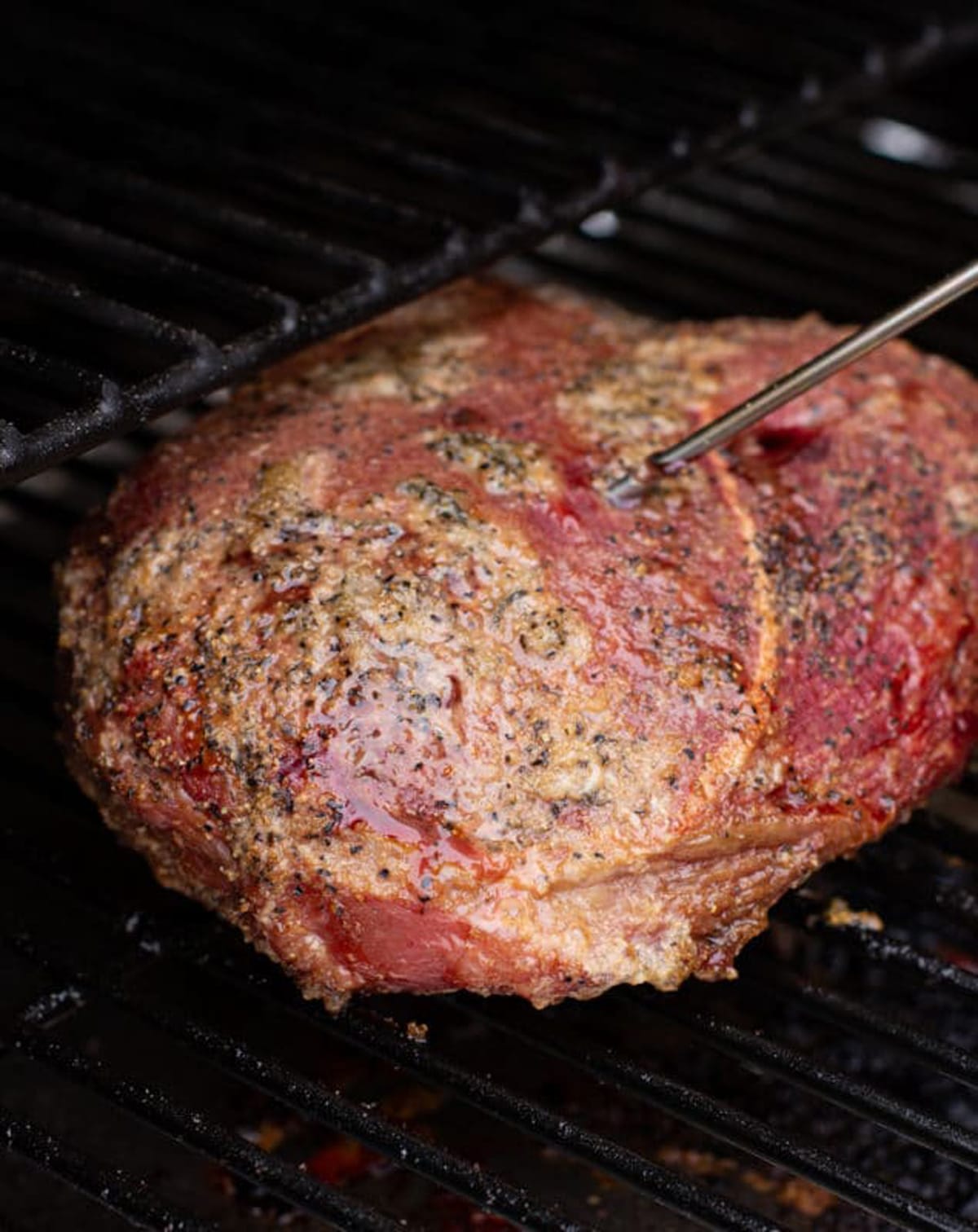 Chuck roast on a smoker with temperature probe inserted. 