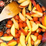Sauteed cherry tomatoes and peaches in a skillet with balsamic vinegar.