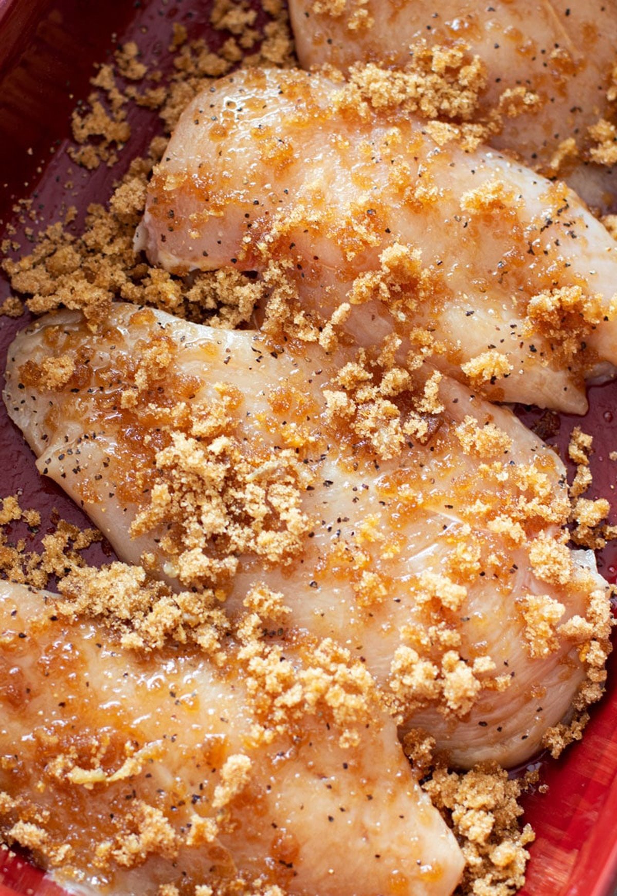 Chicken breasts covered in a garlic and brown sugar rub in a baking dish.