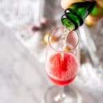 Pouring Champagne into a flute with the minted-cranberry simple syrup and Chambord.