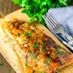 Maple Chipotle Grilled Salmon on a wood plank, fork on table.