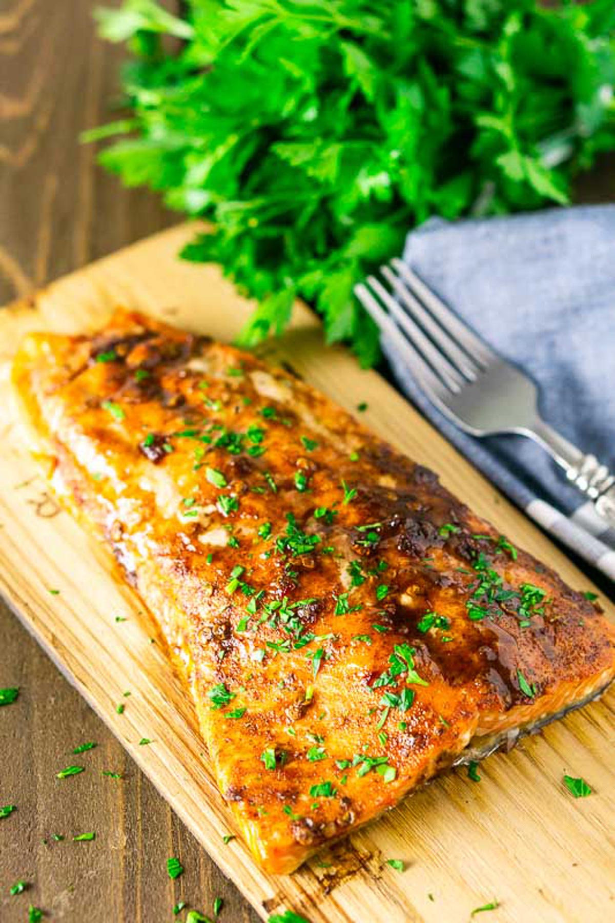 Maple Chipotle Grilled Salmon on a wood plank, fork on table.