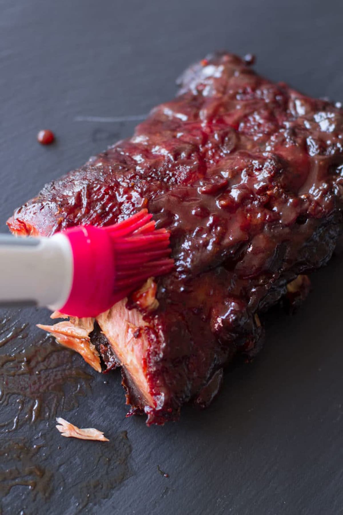 Slab of ribs being basted in BBQ sauce. 