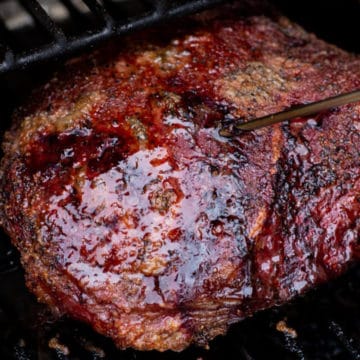 Close up of a smoked chuck roast on a smoker, temperature probe inserted.