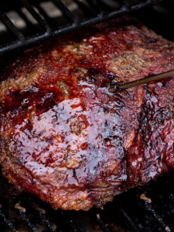 Close up of a smoked chuck roast on a smoker, temperature probe inserted.