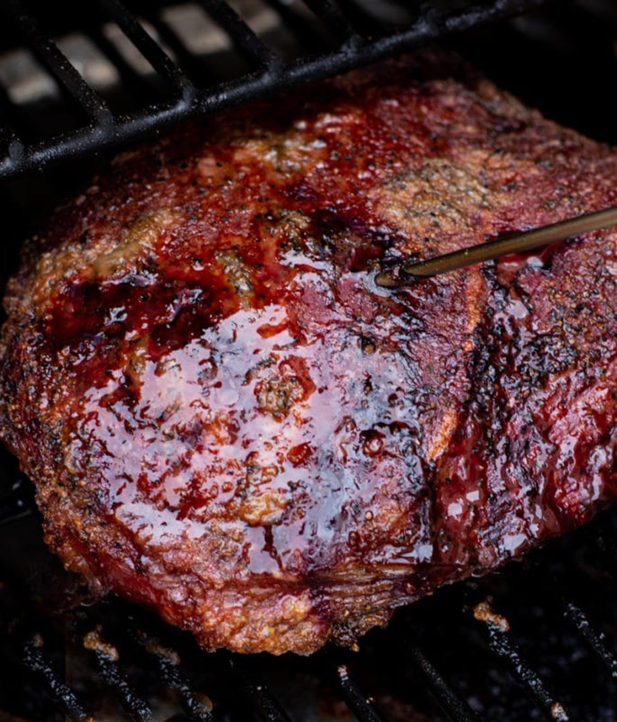 Close up of a smoked chuck roast on a smoker, temperature probe inserted. 