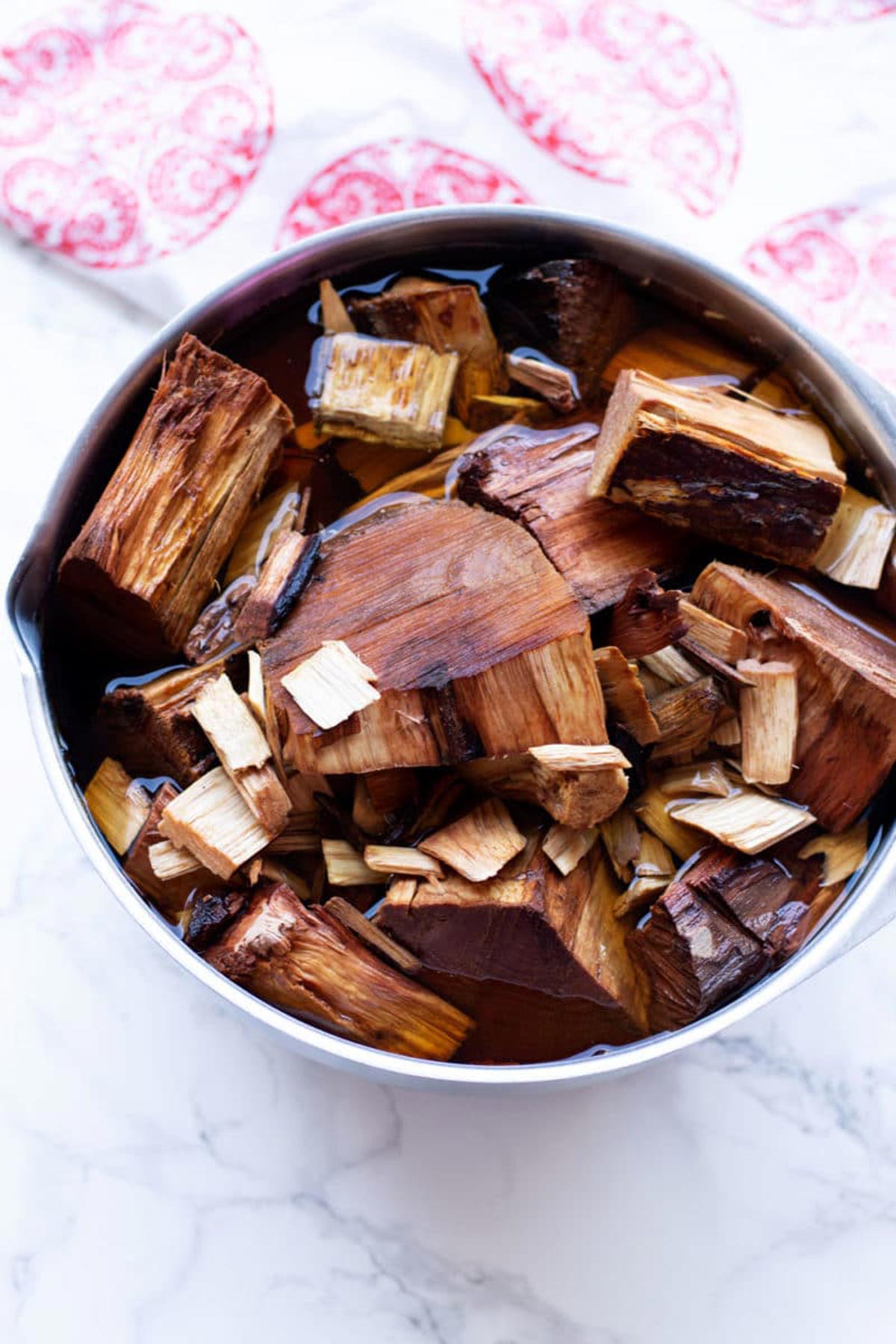 Wood chunks in a silver bowl soaking in water.