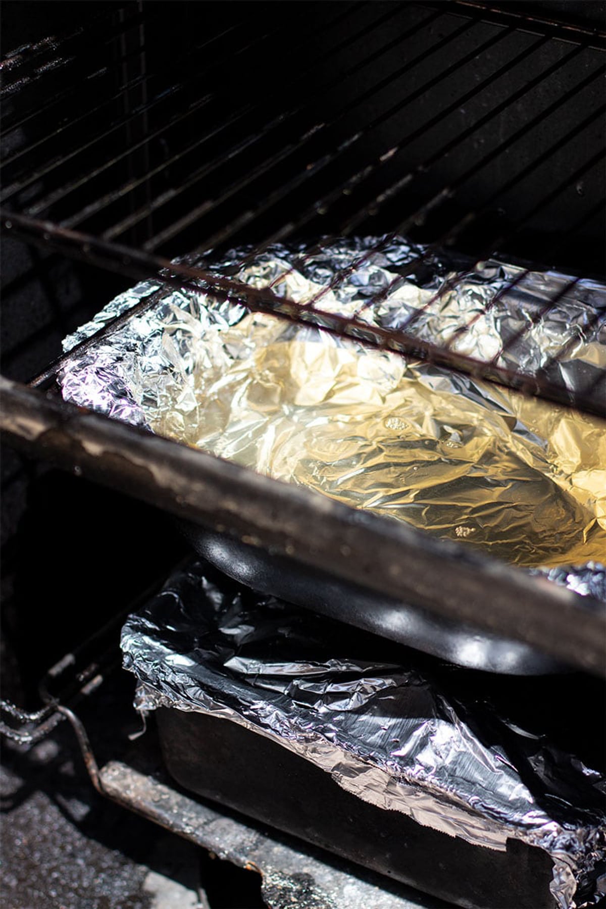 Water pan covered in aluminum foil placed inside a smoker.
