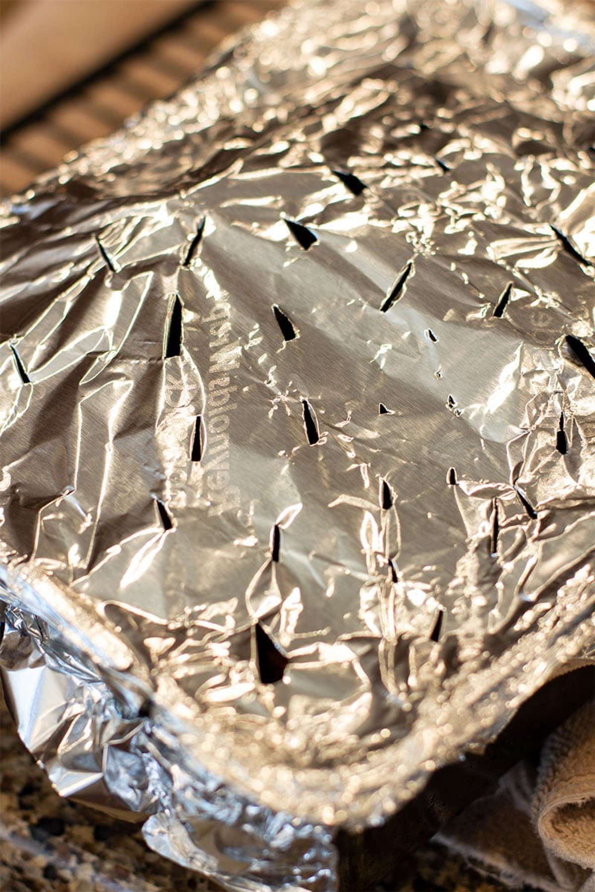 Smoked wood chunk pan covered in aluminum foil with holes poked through.