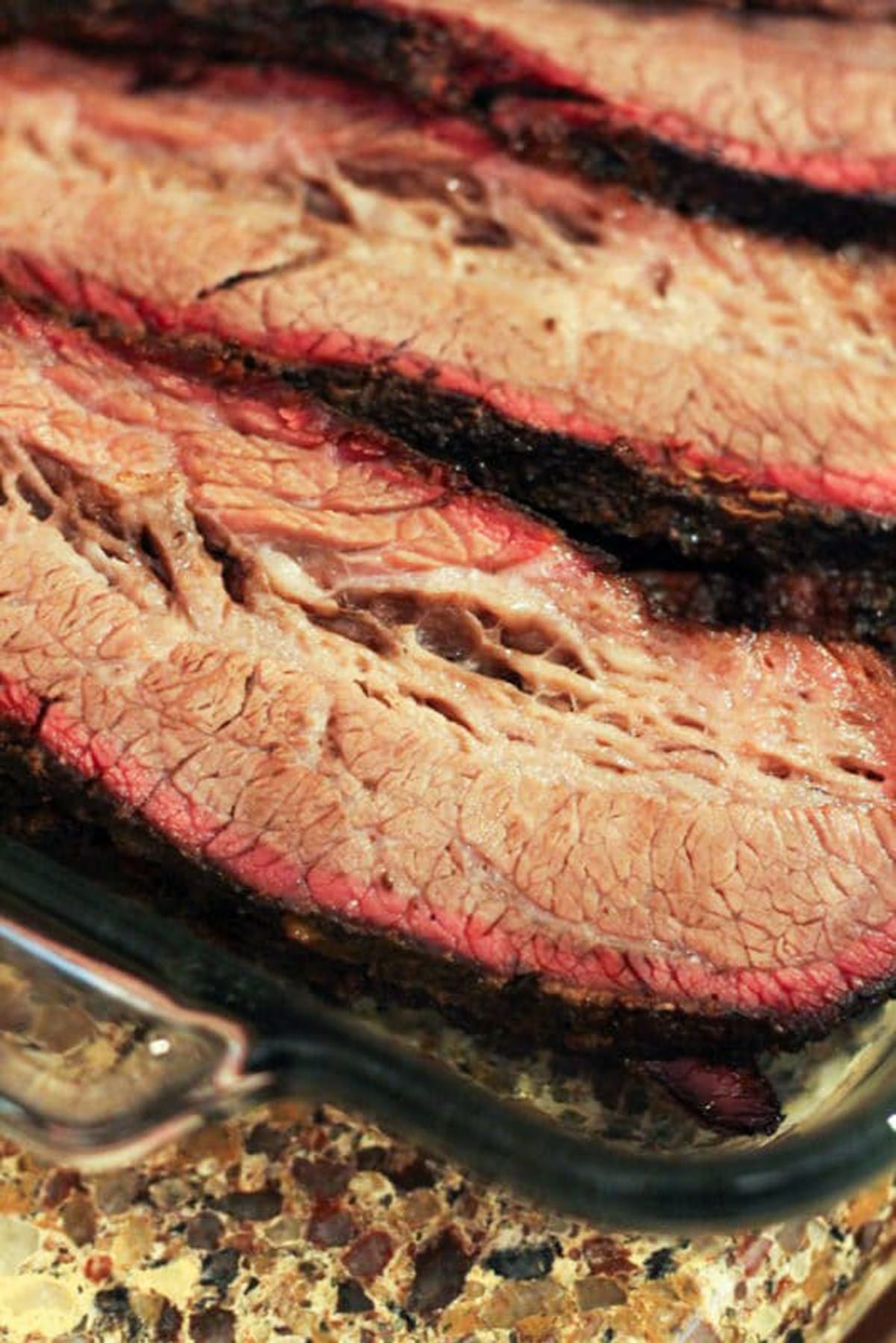 Sliced beef brisket in a platter displaying a smoke ring. 