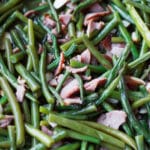 Green beans topped with bacon in a smoker.