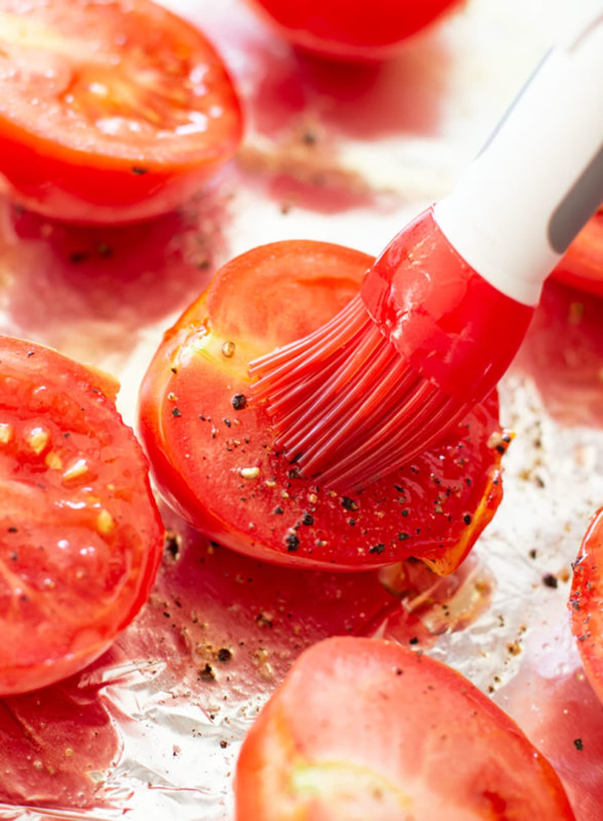 Basting olive oil onto tomato.
