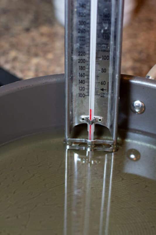 A close up of a digital thermometer measuring the heat of oil.