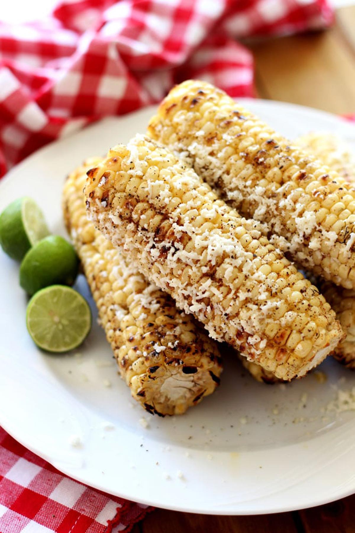 A plate of Corn on the cob and Cotija cheese on a white plate.