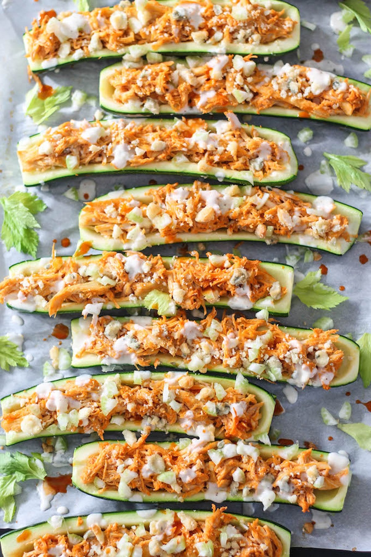A close up of seven long cut zucchinis with shredded chicken.
