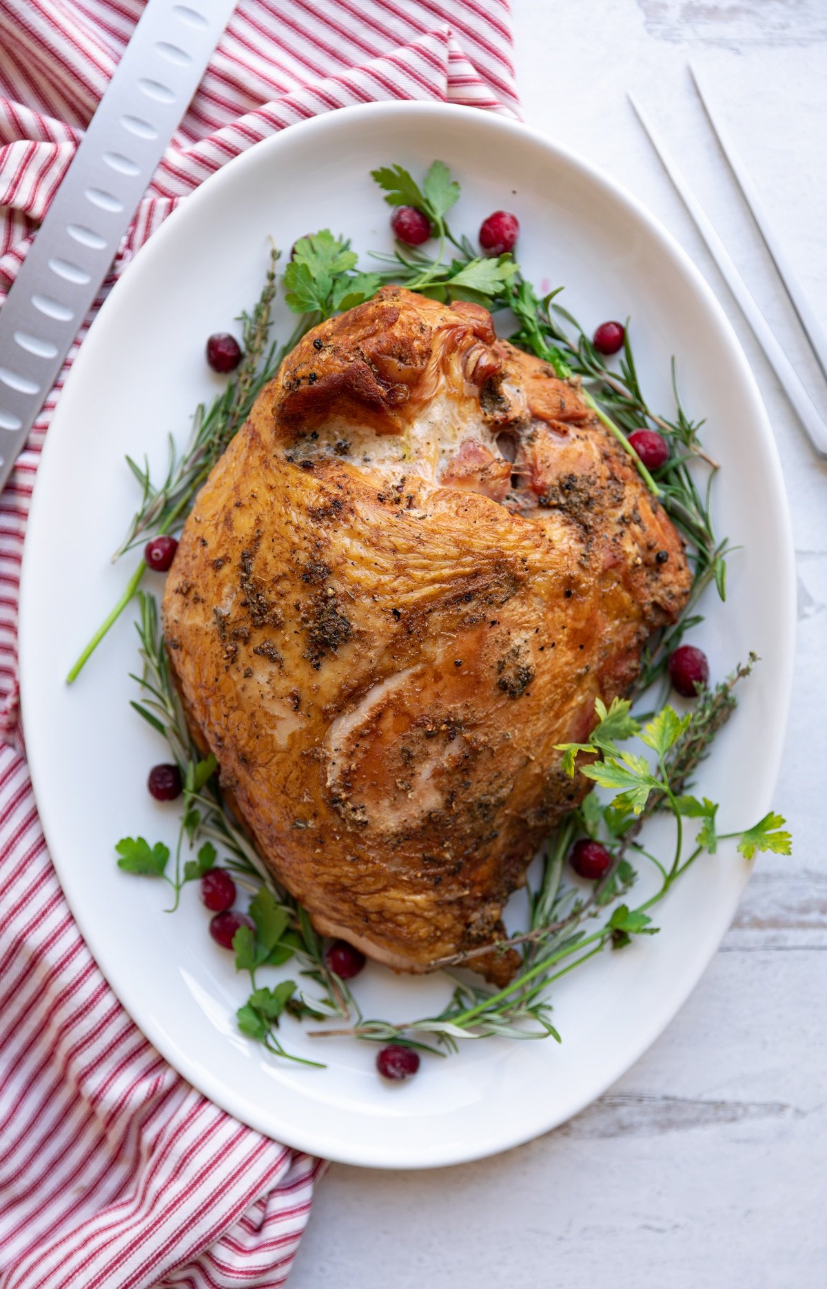 Seasoned turkey breast on platter, knife and fork on counter.