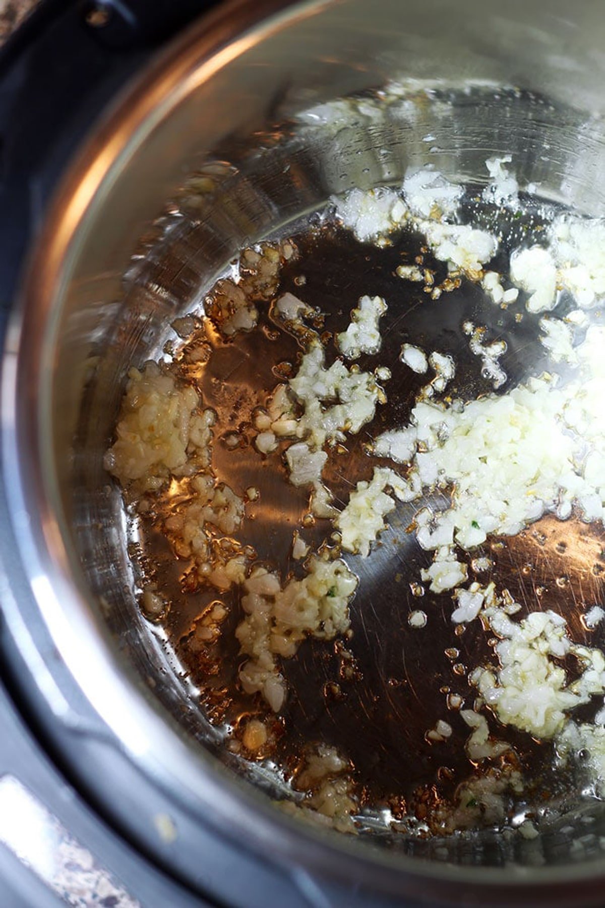Person sauteing minced garlic and onions in a large pot. 