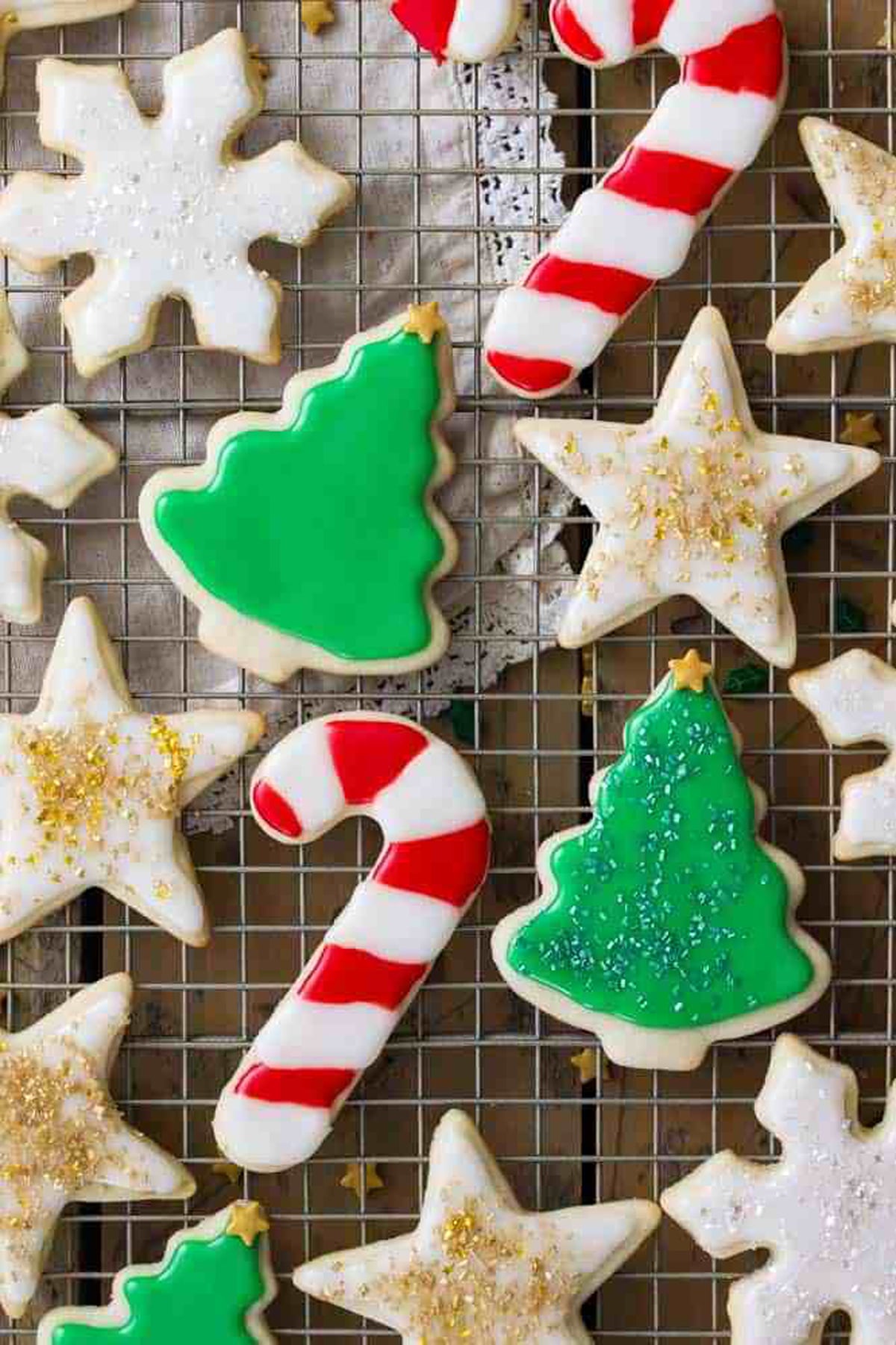 Christmas tree, snowflake, and candy cane sugar cookies on a cooling rack.