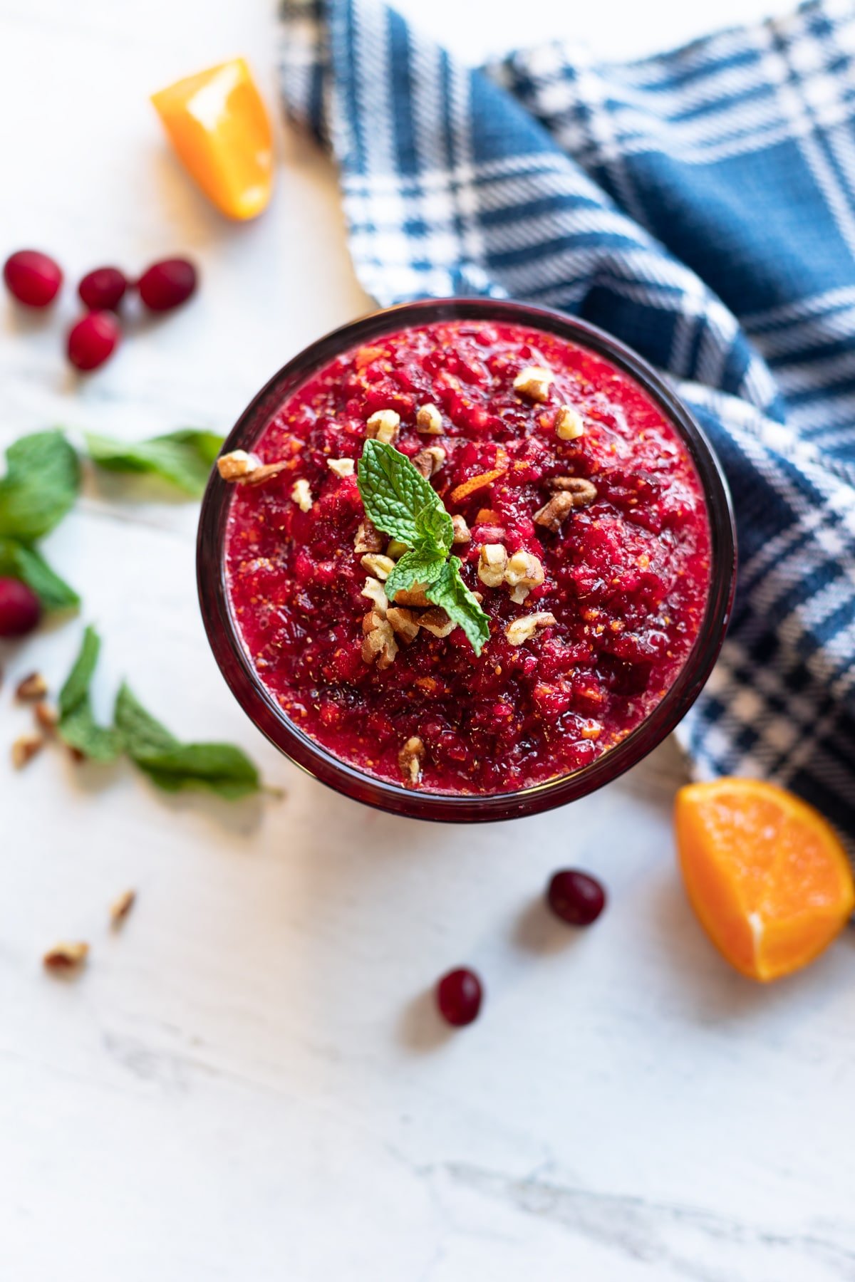 Cranberry relish in a glass bowl topped with chopped pecans, orange zest, and fresh mint. 