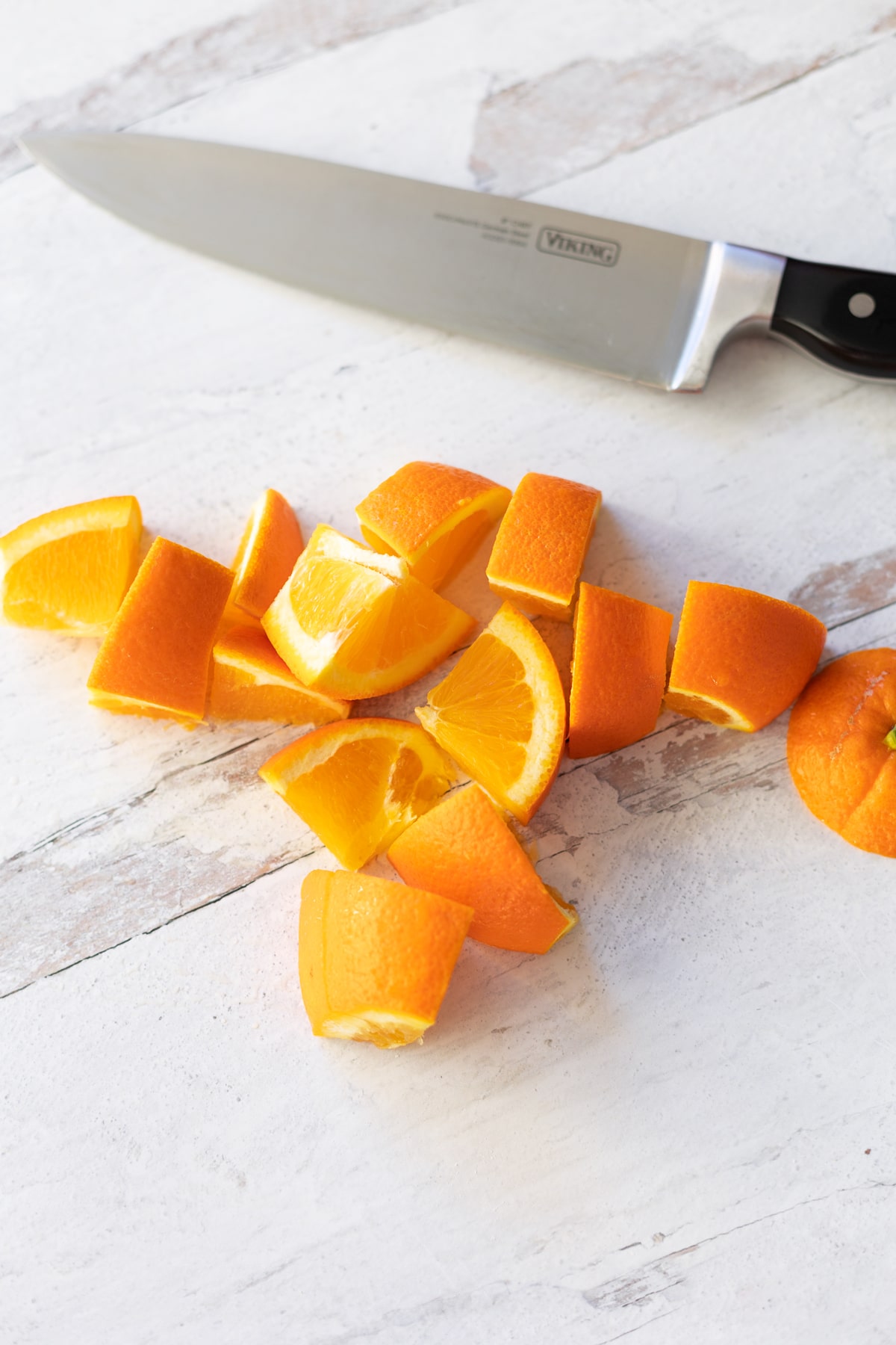 Cut up pieces of fresh orange on a counter alongside a sharp knife. 