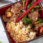 Closeup of beef stir fry with red chop sticks in a bowl with chop sticks.