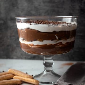 Trifle bowl filled with chocolate pudding, ladyfingers, and whip cream.