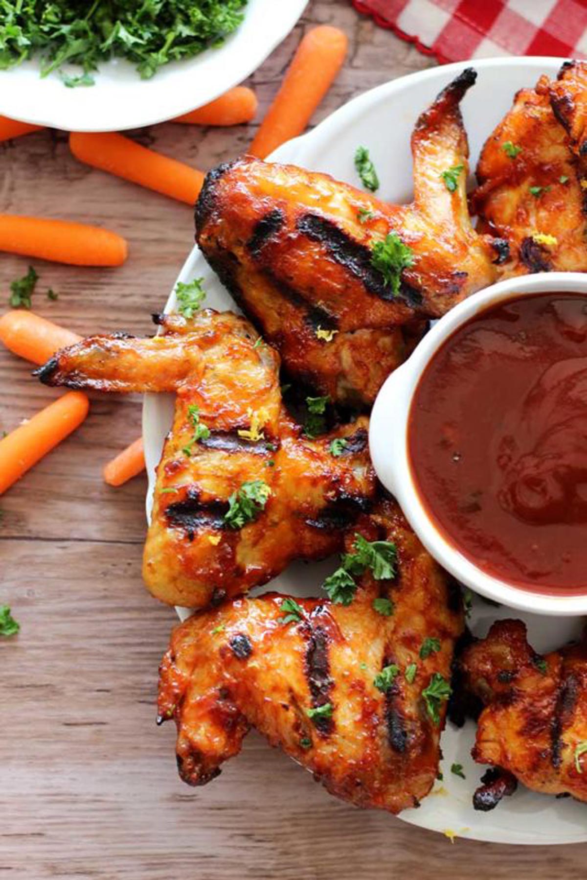 BBQ chicken wings on a white serving plate with dipping sauce.