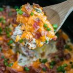 Keto crockpot chicken topped with cheese, bacon, and scallions.