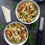 Close-up of two white bowls of rotini pesto pasta with chicken.