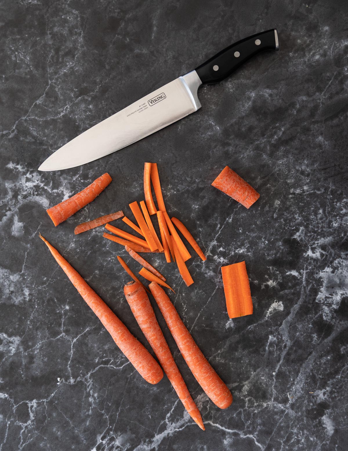 Knife and sliced matchstick carrots on a counter. 