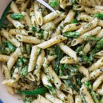 Pot of penne pasta with pesto and asparagus.