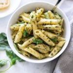 White bowl of noodle, asparagus and pesto sauce.